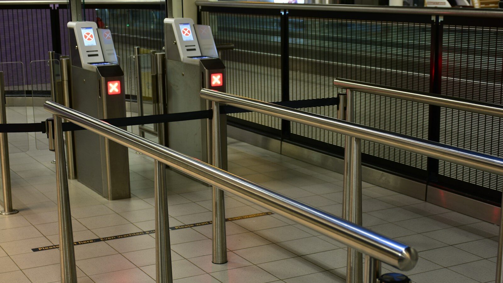 Metal turnstiles and railings at a transit station.