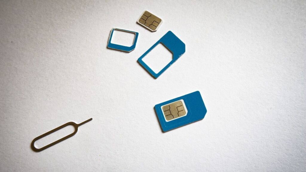 Close-up of SIM cards and ejector tool on white background, emphasizing telecommunication technology.