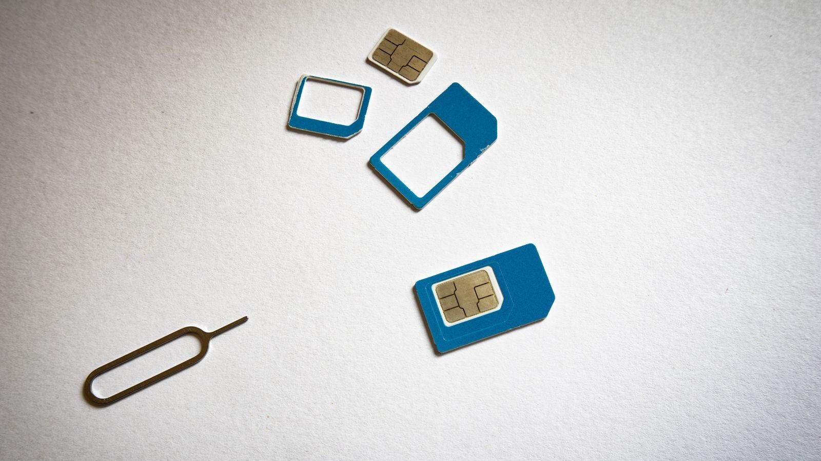 Close-up of SIM cards and ejector tool on white background, emphasizing telecommunication technology.