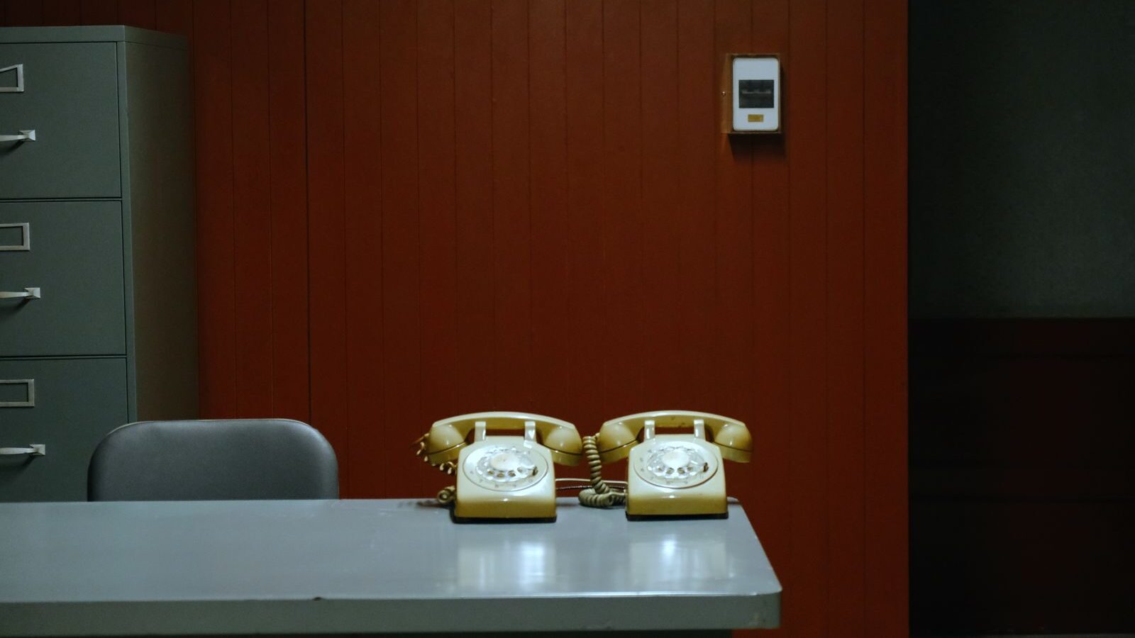 Retro office setup with rotary phones, file cabinet, and red wood paneling in Ho Chi Minh City's Independence Palace.