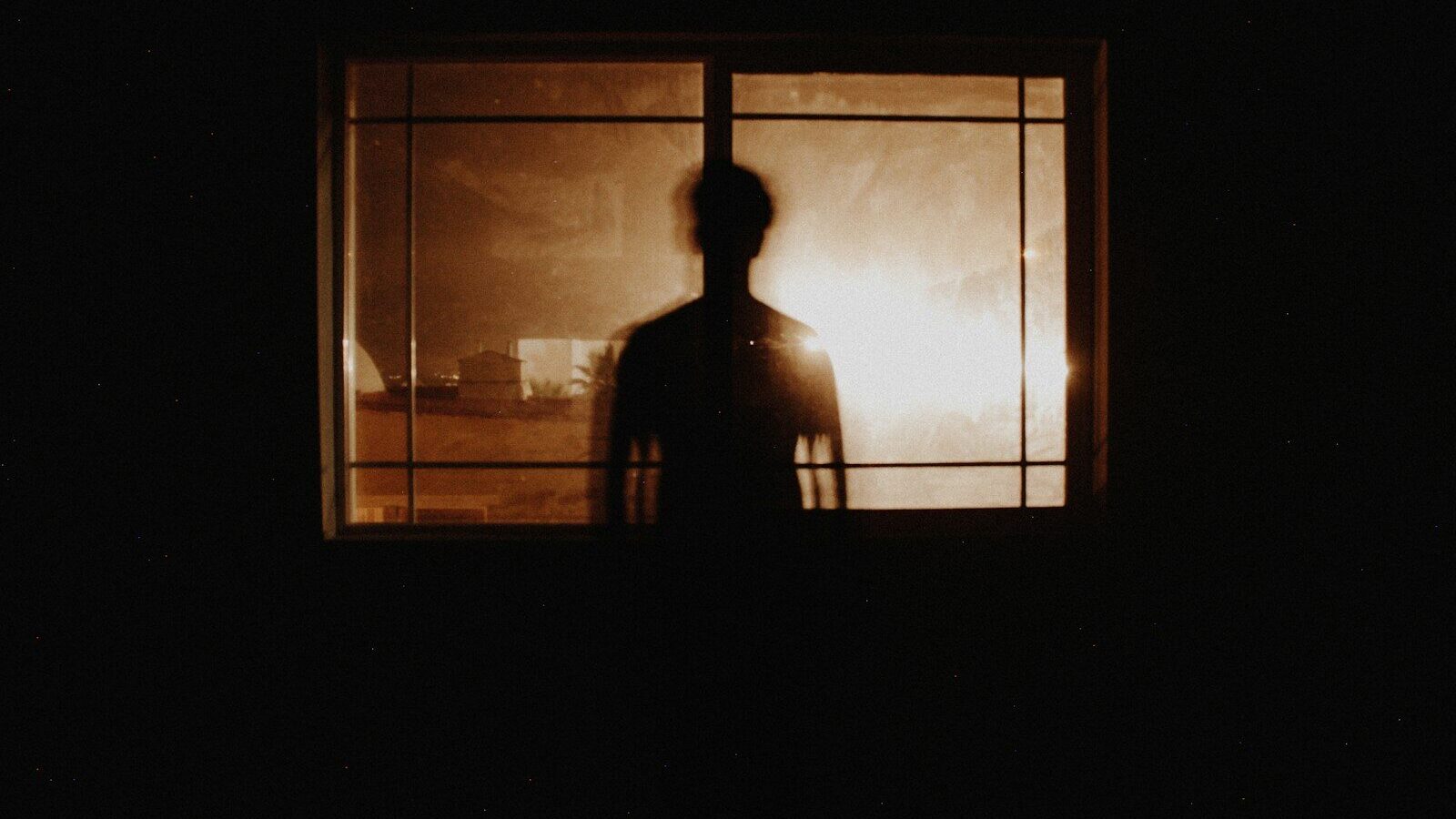 silhouette photography of person in front of window