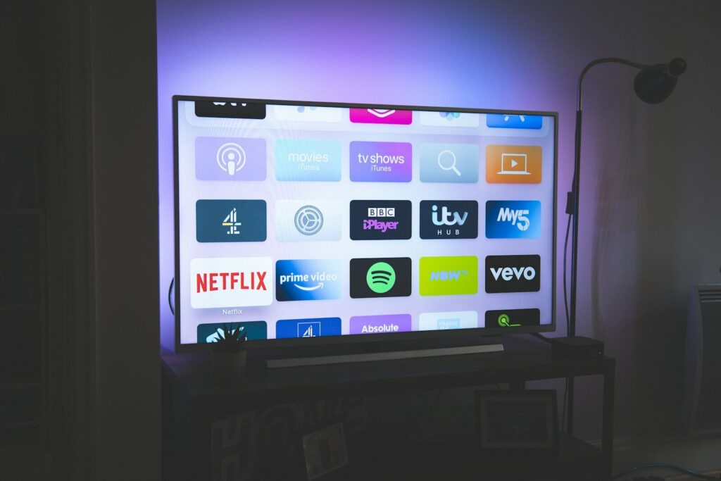A television screen displaying a grid of streaming service app icons in a dim room
